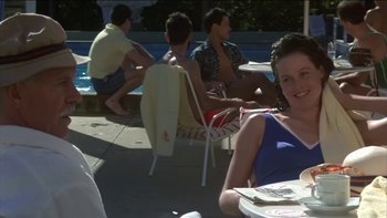 Movie still from “The Year of Living Dangerously” (1982), directed by Peter Weir – A group of people sitting around a swimming pool; Medium shot, Low angle