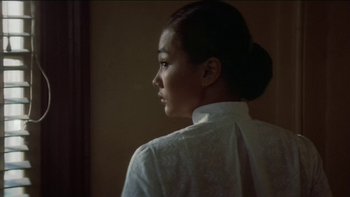 Movie still from “The Year of Living Dangerously” (1982), directed by Peter Weir – A woman in a white shirt looking out a window; Close Up shot, Low angle
