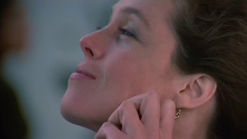 Movie still from “The Year of Living Dangerously” (1982), directed by Peter Weir – A person putting on a earring; Close Up shot, Low angle
