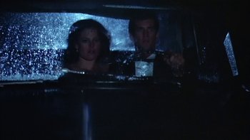 Movie still from “The Year of Living Dangerously” (1982), directed by Peter Weir – A man and a woman in the back of a car; Medium shot, High angle