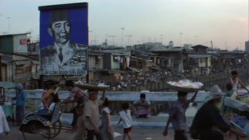 Movie still from “The Year of Living Dangerously” (1982), directed by Peter Weir – A group of people walking down a street near buildings; Wide shot, High angle