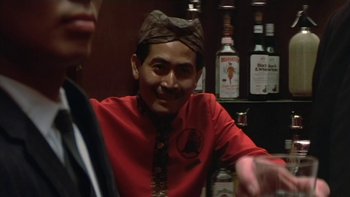 Movie still from “The Year of Living Dangerously” (1982), directed by Peter Weir – A man wearing a red shirt and a tie; Close Up shot, Over the shoulder angle