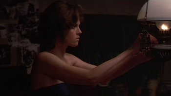 Movie still from “The Year of Living Dangerously” (1982), directed by Peter Weir – A woman sitting in a chair in a dark room; Close Up shot, Low angle