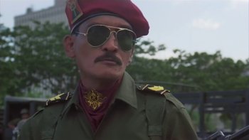 Movie still from “The Year of Living Dangerously” (1982), directed by Peter Weir – A man in a military uniform wearing sunglasses and a red hat; Close Up shot, Low angle