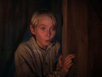Movie still from “The Yearling” (1946), directed by Clarence Brown – A young boy holding a knife up to his face; Close Up shot, Low angle