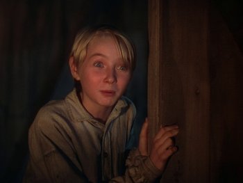 Movie still from “The Yearling” (1946), directed by Clarence Brown – A young man leaning against a wooden wall; Close Up shot, Low angle