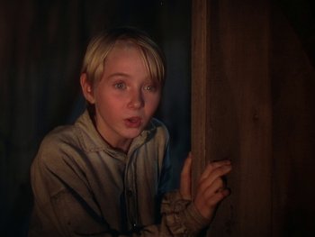 Movie still from “The Yearling” (1946), directed by Clarence Brown – A young boy leaning against a wooden wall; Close Up shot, Low angle