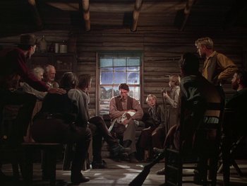 Movie still from “The Yearling” (1946), directed by Clarence Brown – A group of people sitting around in a room; Wide shot, Over the shoulder angle