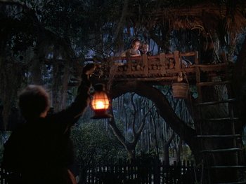 Movie still from “The Yearling” (1946), directed by Clarence Brown – A man holding a lantern while standing on top of a bridge; Wide shot, Low angle