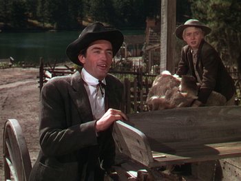 Movie still from “The Yearling” (1946), directed by Clarence Brown – A man wearing a suit and a hat standing next to another man wearing a suit and a hat; Medium shot, Low angle