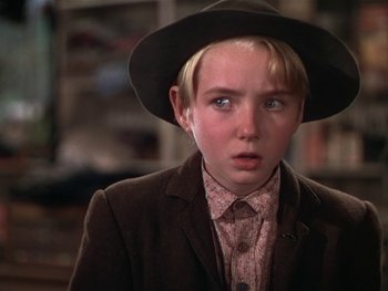 Movie still from “The Yearling” (1946), directed by Clarence Brown – A young boy wearing a hat and a suit; Close Up shot, Over the shoulder angle