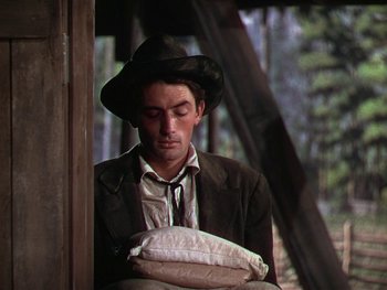 Movie still from “The Yearling” (1946), directed by Clarence Brown – A man wearing a hat and holding a pillow in his hands; Medium shot, Low angle
