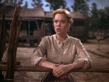 Movie still from “The Yearling” (1946), directed by Clarence Brown – A woman sitting on top of a wooden fence; Medium shot, Over the shoulder angle
