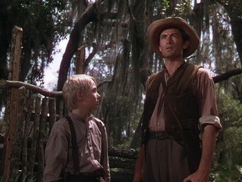 Movie still from “The Yearling” (1946), directed by Clarence Brown – A man and a young boy standing next to each other in the woods; Medium shot, Low angle