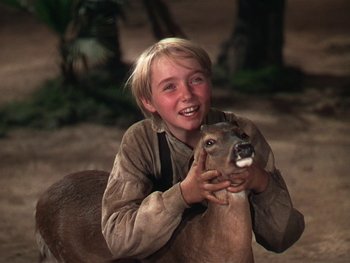 Movie still from “The Yearling” (1946), directed by Clarence Brown – A young boy is petting an animal on his chest; Close Up shot, Over the shoulder angle
