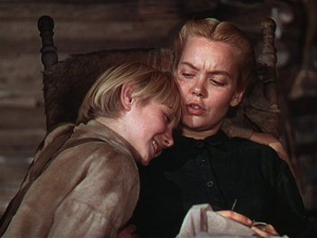 Movie still from “The Yearling” (1946), directed by Clarence Brown – A woman and a child sitting next to each other on a bed; Close Up shot, Low angle