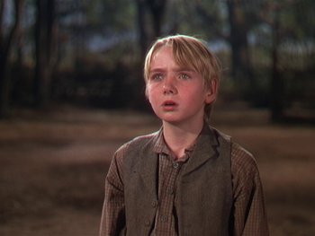 Movie still from “The Yearling” (1946), directed by Clarence Brown – A young boy is standing in a field; Close Up shot, Low angle