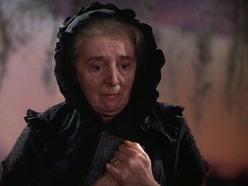Movie still from “The Yearling” (1946), directed by Clarence Brown – An older woman wearing a black hooded cloak; Close Up shot, Low angle