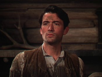 Movie still from “The Yearling” (1946), directed by Clarence Brown – A man in a brown vest standing in front of a wooden wall; Close Up shot, Low angle