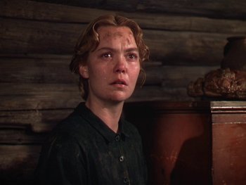 Movie still from “The Yearling” (1946), directed by Clarence Brown – A young woman in a black shirt is standing in front of a wooden wall; Close Up shot, Low angle