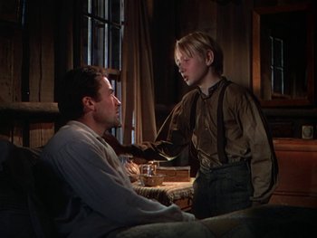Movie still from “The Yearling” (1946), directed by Clarence Brown – A man and a boy are sitting on a couch; Medium shot, Over the shoulder angle