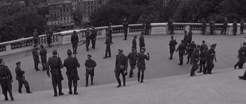 Movie still from “The Young Lions” (1958), directed by Edward Dmytryk – A black and white photo of a group of men standing on a bridge; Extreme Wide shot, High angle