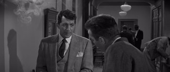 Movie still from “The Young Lions” (1958), directed by Edward Dmytryk – A man in a suit talking to another man in a suit; Medium shot, Over the shoulder angle