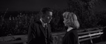 Movie still from “The Young Lions” (1958), directed by Edward Dmytryk – A black and white photo of a man and a woman talking; Medium shot, Low angle