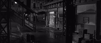 Movie still from “The Young Lions” (1958), directed by Edward Dmytryk – An empty city street at night in the rain; Wide shot, High angle