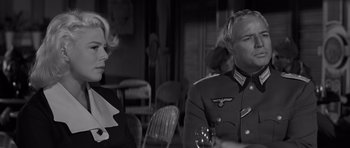 Movie still from “The Young Lions” (1958), directed by Edward Dmytryk – A man and a woman are sitting at a table; Medium shot, Over the shoulder angle