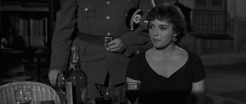 Movie still from “The Young Lions” (1958), directed by Edward Dmytryk – A woman sitting in front of a man holding a wine glass; Close Up shot, Over the shoulder angle
