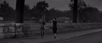 Movie still from “The Young Lions” (1958), directed by Edward Dmytryk – An old photo of a woman and a man walking down the street; Wide shot, High angle