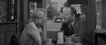 Movie still from “The Young Lions” (1958), directed by Edward Dmytryk – A man and a woman sitting at a table with cups of coffee; Medium shot, Over the shoulder angle