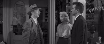 Movie still from “The Young Lions” (1958), directed by Edward Dmytryk – A black and white photo of a man and two women; Medium shot, Over the shoulder angle