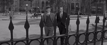 Movie still from “The Young Lions” (1958), directed by Edward Dmytryk – A couple of men walking down a sidewalk; Medium shot, Over the shoulder angle