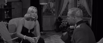 Movie still from “The Young Lions” (1958), directed by Edward Dmytryk – A man taking a picture of a woman in a black dress; Medium shot, Over the shoulder angle