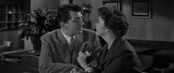 Movie still from “The Young Lions” (1958), directed by Edward Dmytryk – A man and a woman sitting next to each other in a room; Medium shot, Over the shoulder angle