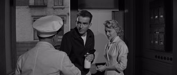 Movie still from “The Young Lions” (1958), directed by Edward Dmytryk – A man and a woman standing next to each other in front of another man; Medium shot, Low angle