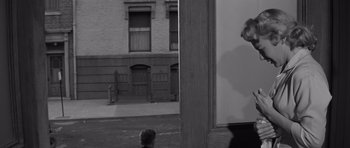 Movie still from “The Young Lions” (1958), directed by Edward Dmytryk – A black - and - white photo of a boy looking out of a window; Medium shot, Over the shoulder angle