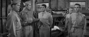 Movie still from “The Young Lions” (1958), directed by Edward Dmytryk – Two men in uniforms are standing in a room; Medium shot, Over the shoulder angle