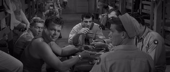 Movie still from “The Young Lions” (1958), directed by Edward Dmytryk – A black and white photo of a group of men sitting at a table; Medium shot, Over the shoulder angle