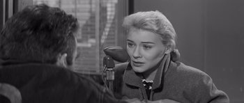 Movie still from “The Young Lions” (1958), directed by Edward Dmytryk – A woman sitting at a table in front of a microphone; Close Up shot, High angle