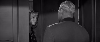 Movie still from “The Young Lions” (1958), directed by Edward Dmytryk – A man and a woman are talking to each other in front of an elevator; Close Up shot, Over the shoulder angle