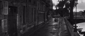 Movie still from “The Young Lions” (1958), directed by Edward Dmytryk – A car driving down a street next to tall buildings; Extreme Wide shot, High angle