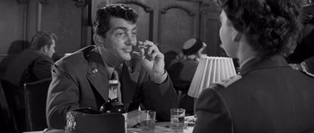 Movie still from “The Young Lions” (1958), directed by Edward Dmytryk – A black and white photo of a man sitting at a table; Medium shot, Over the shoulder angle