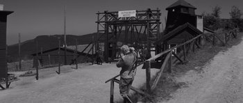Movie still from “The Young Lions” (1958), directed by Edward Dmytryk – An old man standing in front of a wooden structure; Wide shot, Low angle