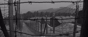 Movie still from “The Young Lions” (1958), directed by Edward Dmytryk – A black - and - white photo of a barbed - wire fence; Extreme Wide shot, High angle
