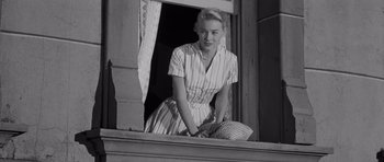 Movie still from “The Young Lions” (1958), directed by Edward Dmytryk – A black and white photo of a woman looking out of a window; Medium shot, Low angle