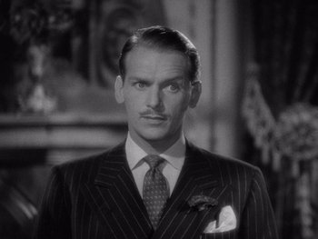 Movie still from “The Young in Heart” (1938), directed by Gilbert Pratt – A man wearing a suit and tie in front of a mirror; Close Up shot, Low angle