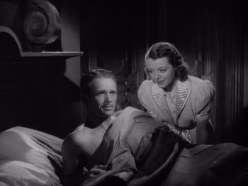 Movie still from “The Young in Heart” (1938), directed by Gilbert Pratt – A man and a woman are sitting on a bed together; Medium shot, High angle